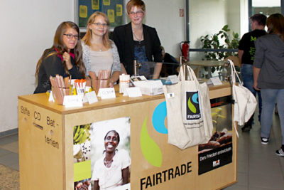Drei Schülerinnen stehen am einen Stand zum Thema Fairtrade